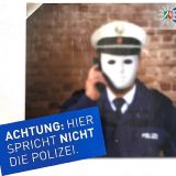 Uniformierter Polizeibeamter mit weißer Gesichtsmaske. Der Beamter hält einen Telefonhörer in der Hand. Dazu steht in einem Banner: Achtung - hier spricht nicht die Polizei. Oben rechts ist das Logo der Kreispolizeibehörde zu sehen.