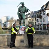 Zwei Polizeibeamtinnen in Uniform präsentieren das Plakat zur Kampagne Besser ohne Messer auf der Siegbrücke in der Siegener Innenstadt