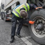 Polizeibeamter kontrolliert Reifen bzw. Räder eines Lkw