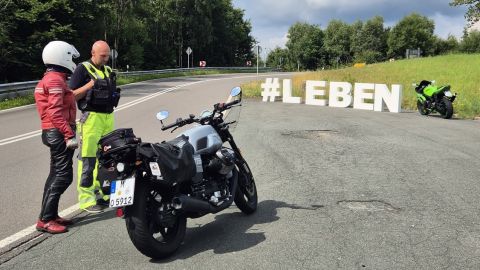 Biker im Gespräch mit einer Fachkraft des VD bei Aktion Hashtag LEBEN in der Applauskurve