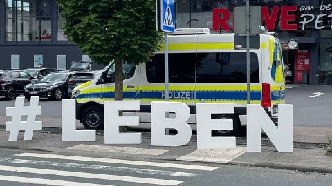 Man sieht die Buchstaben #Leben auf einem Zebrastreifen mit Streifenwagen im Hintergrund